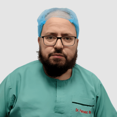 Person wearing a green scrub top and blue surgical cap, seen from the shoulders up.